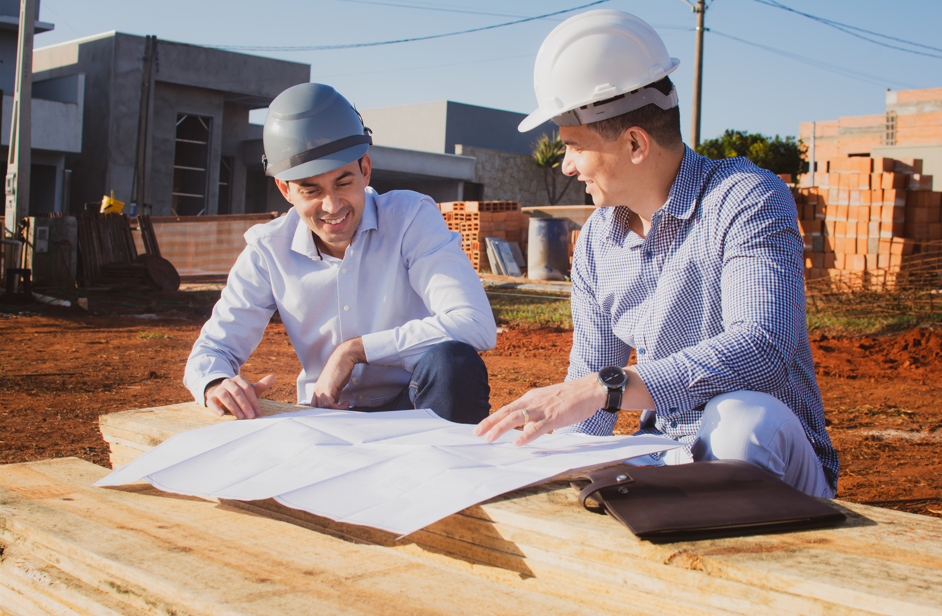 Engenheiros da LU Engenharia analisando plantas estruturais em canteiro de obras, representando o laudo estrutural técnico